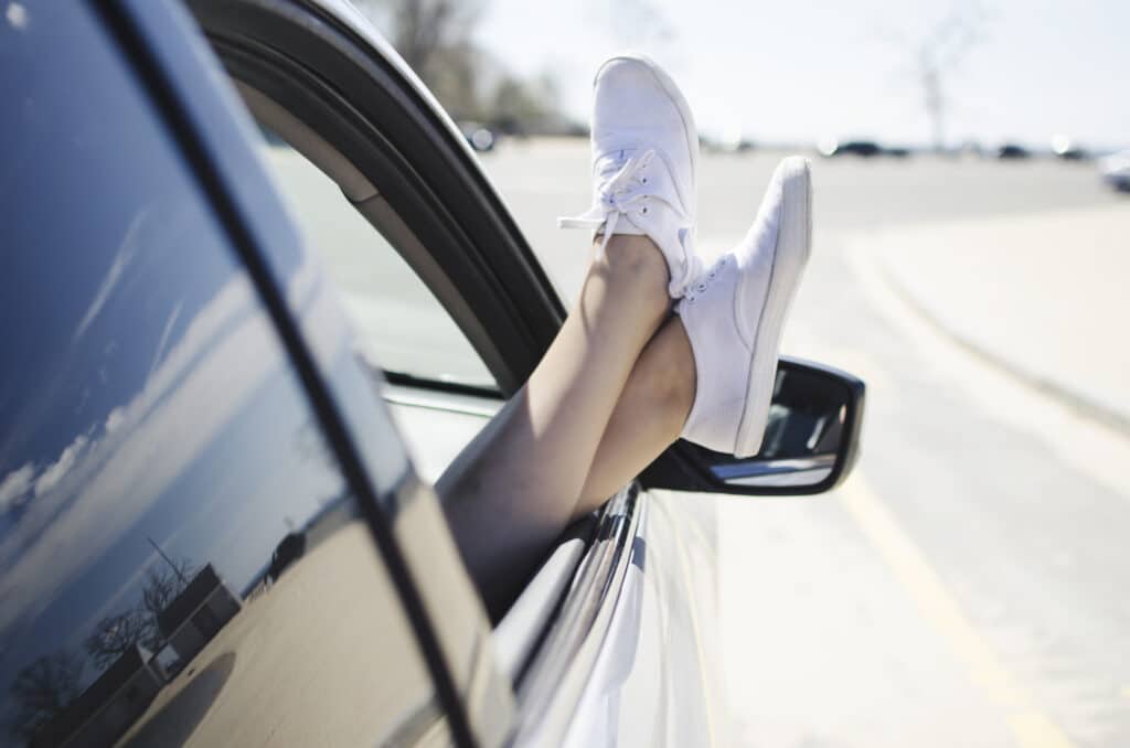 Des pieds dépassant de la fenêtre d'une voiture qui roule