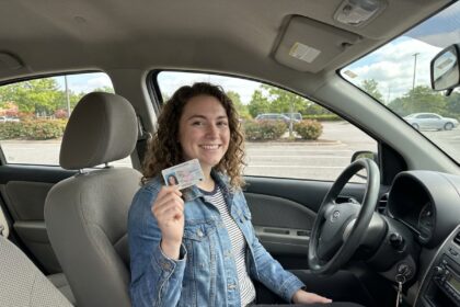 Jeune femme souriante avec permis dans la voiture