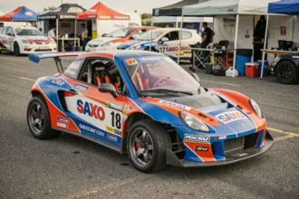 Kit car Saxo préparé pour la course club dans un paddock, avec carrosserie élargie et cage de sécurité visible